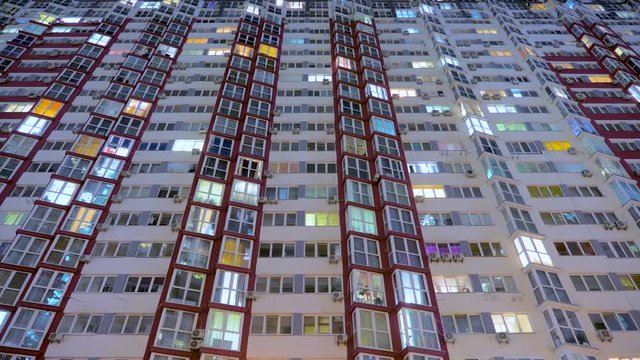 Timelapse of apartment windows at dusk to night. Nighttime time lapse of illuminated building windows at night with people living in flats with balcony. View from below. Business center outdoor