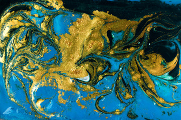 Liquid uneven blue and green marbling pattern with golden glitter and glare of light