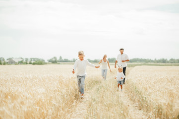 Happy family run in wheat field in sunny day