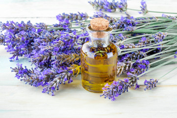 Lavender essential oil with fresh lavender flowers on a rustic wooden background with a place for text