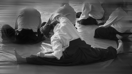 Black and white image of aikido. ?thlete The girl is warming up before training. Gymnastic Twine....