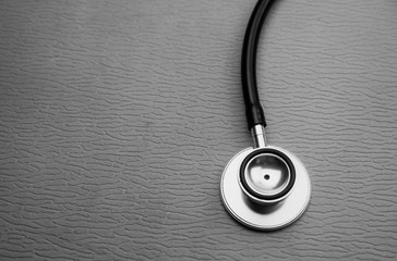 Fototapeta na wymiar Head of stethoscope put at the rignt side of background,abstract art design background,black and white tone,blurry light around