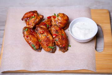 BBQ chicken wings with sauce on paper. Close-up, selective focus.