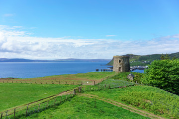Fototapeta na wymiar Uig Tower or Captain Fraser's Folly viewing Uig harbour in the background in summer , Isle of Skye , Scotland