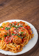 pasta spaghetti with meatballs in tomato sauce on a plate on dark wooden background