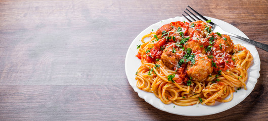 pasta spaghetti with meatballs in tomato sauce on a plate on dark wooden background