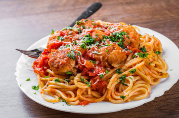 pasta spaghetti with meatballs in tomato sauce on a plate on dark wooden background