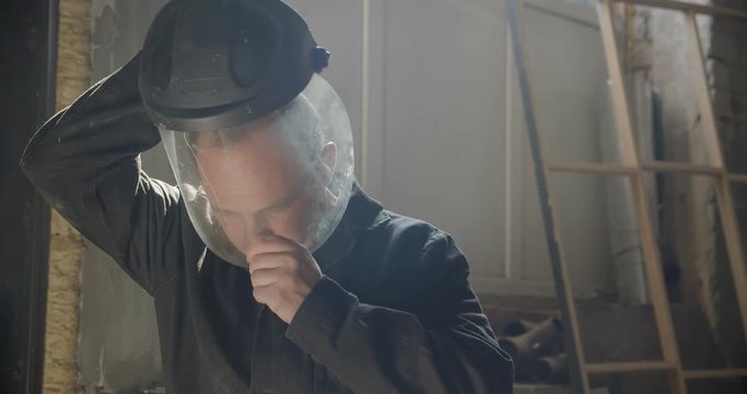 Middle-aged male professional carpentry master wears safety mask at wood manufacture preparing for work.