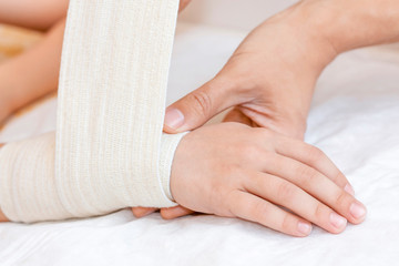 Broken wrist with bandage in hospital office. Doctor is bandaging limb of patient. Sprain, stress...