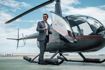Businessman standing near private helicopter - obrazy, fototapety, plakaty