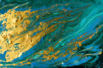 Liquid uneven blue and green marbling pattern with golden glitter and glare of light