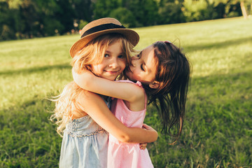 Outdoors closeup portrait of two adorable children shares love and frienship. Two little girls...
