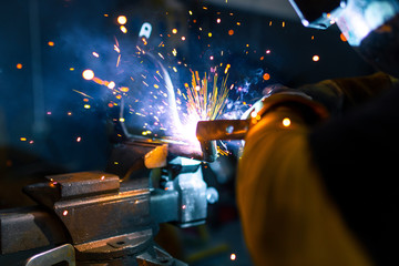 Worker welding a metal part using a machine with sparks. close-up.