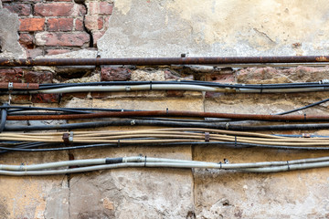 bundle of electrical wires and communication cables on a brick wall of an old house