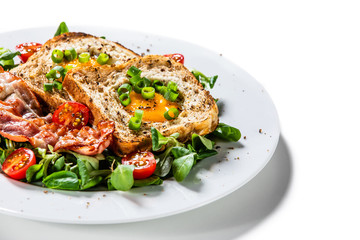 Breakfast - toasted bread with fried egg, bacon and vegetables
