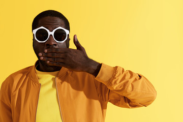 Surprise. Shocked man in fashion sunglasses on yellow background - obrazy, fototapety, plakaty
