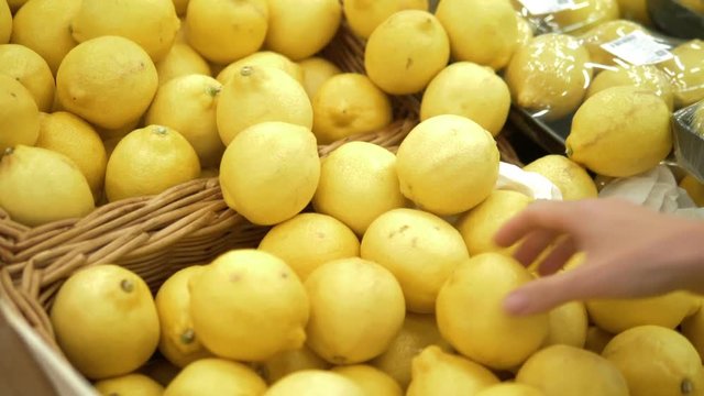 close-up. Woman's hand picking a lemon on the counter in the supermarket