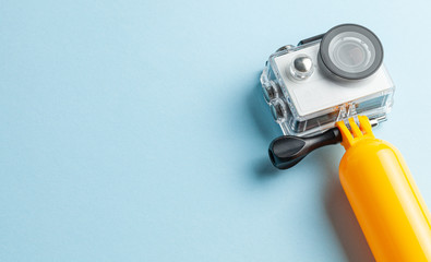 Action camera in a waterproof box and a buoy for diving on a blue background. Copy space for text.
