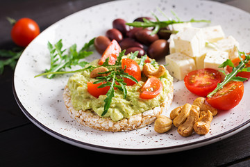 Healthy avocado toasts for breakfast or lunch,  guacamole avocado, kalamata olives, tomatoes, cashew nuts and  feta cheese. Vegetarian sandwiches