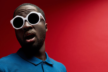 Surprised black man in fashion sunglasses on background portrait