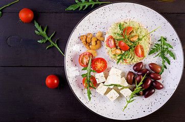 Healthy avocado toasts for breakfast or lunch,  guacamole avocado, kalamata olives, tomatoes, cashew nuts and  feta cheese. Vegetarian sandwiches. Top view