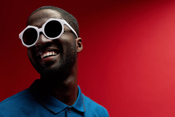 Fashion. Smiling black man in sunglasses on background portrait