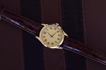 Gold and quartz watch with leather strap.