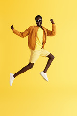 Fototapeta na wymiar Jump. Happy man jumping in air and laughing on yellow background