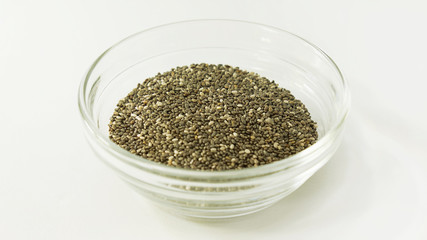 Isolated small glass bawl with raw chia seeds,  popular ingredient in smoothies, breakfast cereals, energy bars, granola bars, yogurt, tortillas, and bread for weight loss and nutritional benefits 