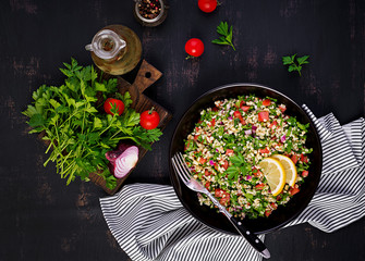 Tabbouleh salad. Traditional middle eastern or arab dish. Levantine vegetarian salad with parsley, mint, bulgur, tomato. Top view