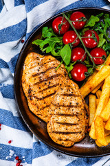 Grilled chicken fillet with french fries on wooden table
