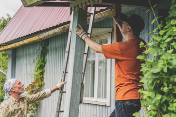 Two male workers are engaged in repairing a country house.