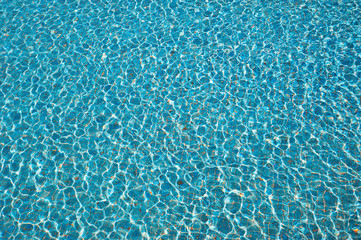 Swimming pool water background with texture of water surface with ripple effect, concept for summer vacation or spa, relaxation or working from anywhere, natural pattern with copy space