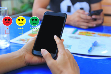 Young woman hand holding smartphone and putting check mark with smiley face marker and green marker on five stars of delivery package, Satisfaction evaluation and Postal service concept