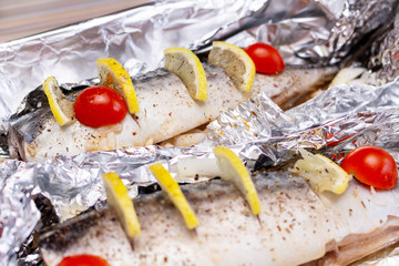 Fototapeta na wymiar Raw mackerel on the foil with lemon and cherry tomatoes and spices healthy delicious tasty food