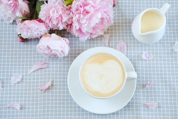 cappuccino with milk on a gray napkin in peonies