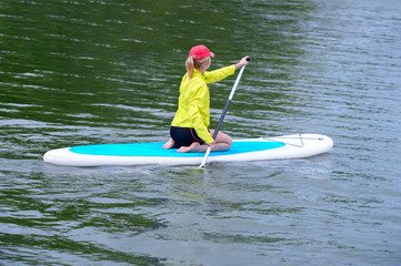 Woman sitting on sup board and enjoying turquoise transparent water.  water activity concept.