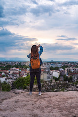 Girl is making selfie during warm summer sunset from Nebet tepe Hill in Plovdiv city, Bulgaria. 