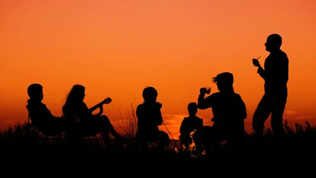 people sitting on the beach with campfire at sunset