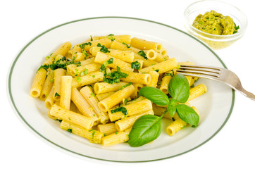 Penne pasta with spinach basil pesto sauce on white plate.