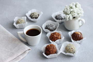 Chocolate candies, a cup of coffee and a bunch of flowers for Valentine's Day on gray table.