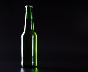 Isolated light green beer bottle on a black background.
