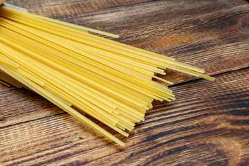 spaghetti, macaroni, pasta, linguine durum wheat Italian thin long on wooden background close up...