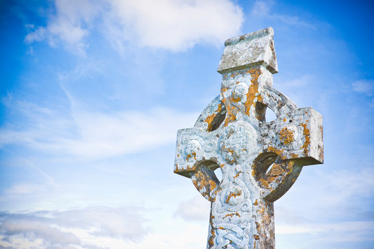 Celtic carved stone cross against a sky background - image with copy space