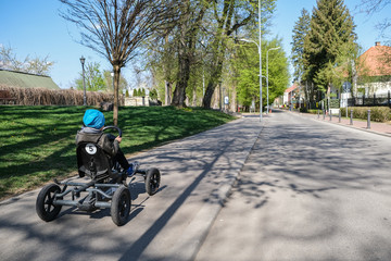 Fototapeta na wymiar un bambino viaggia su una strada con una macchina a pedali