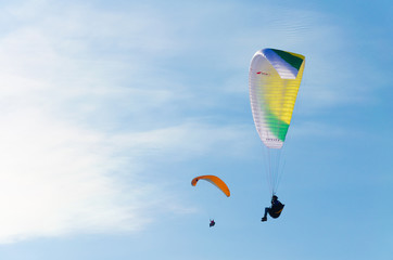 Paragliding in the sky. Two paraglider fly over the mountain valley. Competitions with paragliding,...