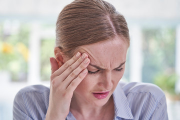 Stressed Businesswoman Suffering With Headache In Office