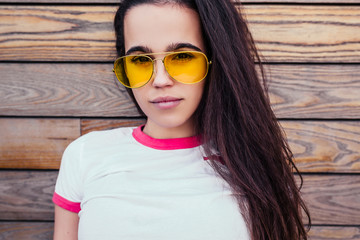Young self-confident and serious girl student in stylish clothes is posing against the background...