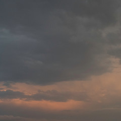 Dramatic dark clouds in the sky with orange sunlight color on the clouds.