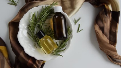 Bottles with rosemary essential oil. Herbal cosmetic treatment products